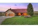 Inviting stone and log cabin with a red roof, two-car garage, and a charming wagon accent at 5351 Tall Horse Trl, Sedalia, CO 80135