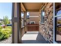 Covered front porch with stone accents and wood pillars providing a cozy outdoor space with view to the neighborhood at 25046 E Bayaud Pl, Aurora, CO 80018