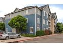 Apartment building with blue siding, well-maintained landscaping, and parking area at 4451 S Ammons St # 2-204, Littleton, CO 80123