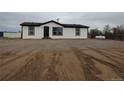 Exterior view of the house with fresh white paint, black trim, gray gravel, a propane tank, and tire tracks at 7486 Harold St, Fort Lupton, CO 80621