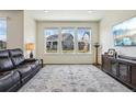 Bright living room featuring hardwood floors, large windows, modern decor, and a comfortable leather sofa at 12797 Clearview St, Firestone, CO 80504