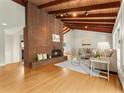 Bright living room with hardwood floors, a brick fireplace, exposed wood beams, and large windows for natural light at 1075 Dudley St, Lakewood, CO 80215