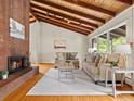 Inviting living room with hardwood floors, wood ceiling beams, a brick fireplace, and comfortable seating area at 1075 Dudley St, Lakewood, CO 80215