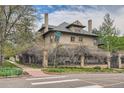 Street view of brick home featuring a wrought iron fence and mature trees at 680 N Emerson St, Denver, CO 80218