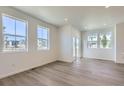 Bright living room with light hardwood floors, white walls, and large windows for plenty of natural light at 2018 S Haleyville Way, Aurora, CO 80018