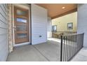 Covered front porch with modern door, stone accents, and a sleek railing at 3390 Cranston Cir, Littleton, CO 80126