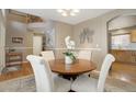 Bright dining area with a round wood table, four upholstered chairs, and decor, open to the kitchen at 4053 S Riviera St, Aurora, CO 80018