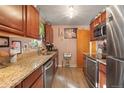 Galley kitchen featuring wood cabinets, stainless steel appliances, and granite countertops at 3023 S Fenton St, Denver, CO 80227