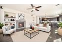 Inviting living room featuring a cozy fireplace, a ceiling fan, and an open layout to the kitchen at 6370 Twilight Ave, Firestone, CO 80504