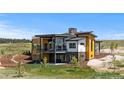 Modern home with large windows and a balcony surrounded by a large yard on a sunny day at 11115 Evening Hunt Rd, Franktown, CO 80116