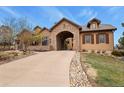 A beautiful stone-accented home featuring a porte-cochère and well-manicured lawn with rock detail at 4839 Bandera Pl, Parker, CO 80134