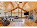 Cozy living room boasts a stone fireplace, hardwood floors, and large windows offering natural light and scenic views at 2218 Witter Gulch Rd, Evergreen, CO 80439