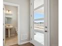 Bright entryway featuring a modern glass door and a view into the downstairs half-bathroom at 2283 Serenidad St, Brighton, CO 80601