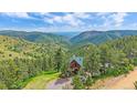 Breathtaking aerial view of a mountain cabin surrounded by towering pine trees at 10390 Hondah Dr, Littleton, CO 80127