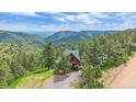 Charming exterior view of a secluded cabin nestled in a lush, green mountain landscape at 10390 Hondah Dr, Littleton, CO 80127