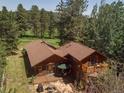 Back of home with a wood deck, patio and fire pit, nestled next to a golf course and trees at 29090 Golf Way, Evergreen, CO 80439