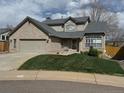 Charming two-story brick home with a well-maintained lawn and a two-car garage on a cloudy day at 6454 S Nelson Way, Littleton, CO 80127