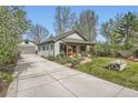 Exterior view of home featuring a long driveway leading to detached garage and lovely landscaping at 4965 Dover St, Arvada, CO 80002