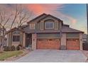 Charming two-story home with a three-car garage, showcasing brick accents, and a well-kept lawn at 16873 Boreas Ct, Parker, CO 80134