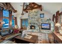 Cozy living room with a grand stone fireplace, wood beams, and leather furniture at 59 Gold Run Rd, Breckenridge, CO 80424