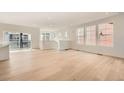 Spacious, light-filled open-concept living space with hardwood floors, many windows, and sleek white walls at 2058 S Haleyville Way, Aurora, CO 80018