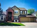 Charming two-story home with brick accents, mature trees, and a well-manicured lawn at 822 Shadowstone Dr, Highlands Ranch, CO 80129
