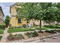 Yellow two-story house boasting a lush front yard with flowering plants and an ornamental tree at 9311 E 5Th Ave, Denver, CO 80230