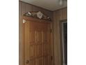 Close up on paneled wood door with flower accent in hallway with wood paneled walls at 7795 Raritan St, Denver, CO 80221