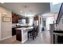 Well-lit kitchen features a breakfast bar, stainless steel appliances, and dark wood cabinets at 4100 Albion St # 1509, Denver, CO 80216