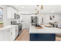 Bright kitchen featuring white cabinets, an island with a navy base, and stainless steel appliances at 1070 W Oxford Ave, Englewood, CO 80110