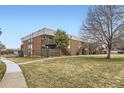 Brick condo building with stairs to the units and a grassy yard with mature trees in a quiet neighborhood at 3663 S Sheridan Blvd # 14, Denver, CO 80235