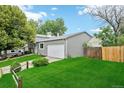 Side view of home featuring a well-manicured lawn, attached garage, and complemented by mature trees at 3932 S Pagosa St, Aurora, CO 80013