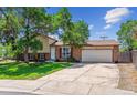 Traditional two-story brick home with mature trees, attached two-car garage, and well-manicured lawn at 5372 E 108Th Pl, Thornton, CO 80233
