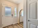 Bright entryway featuring a glass paneled front door, wood floors, and a charming arched mirror at 65 Avocet Ct, Longmont, CO 80501