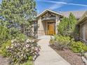 Inviting front entrance with a wooden door, stone accents, and flowering plants lining the walkway at 5149 Raintree Dr, Parker, CO 80134