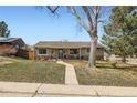 Inviting single-story home with a well-maintained lawn, mature trees, and a charming front porch at 1801 S Meade St, Denver, CO 80219