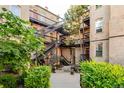 Charming courtyard view with staircases, wrought iron railings, brick walls, and lush greenery at 1210 E Colfax Ave # 104, Denver, CO 80218
