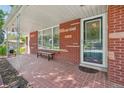 Welcoming covered front porch with a brick floor and a comfortable bench for enjoying the outdoors at 4895 S Galapago St, Englewood, CO 80110