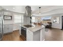 Open concept kitchen with island, stainless steel appliances, granite countertops, and hardwood floors at 8074 Grove St, Westminster, CO 80031