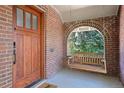Covered front porch with a hanging swing, wood door and brick archway at 1278 Dexter St, Denver, CO 80220