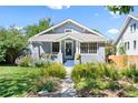 Charming blue bungalow with a well-manicured lawn and lush flowerbeds leading to the front door at 4429 Winona Ct, Denver, CO 80212