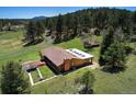 Aerial view showcasing the home's layout with a spacious yard, driveway, and lush surroundings at 1971 Kerr Gulch Rd, Evergreen, CO 80439