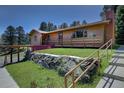 Charming home exterior featuring a cozy front porch with flower boxes and stone retaining wall at 1971 Kerr Gulch Rd, Evergreen, CO 80439