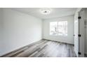 Bright bedroom featuring new gray flooring, white walls and trim, and a large window at 956 S Peoria St, Aurora, CO 80012