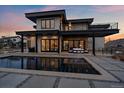 Stunning modern home featuring a backyard pool with expansive patio and sleek architectural design at twilight at 5263 Creation Rock Trl, Morrison, CO 80465