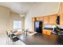 Bright kitchen featuring wooden cabinets, black appliances, and an island with bar seating and a stainless sink at 9585 Pearl Cir # 203, Parker, CO 80134