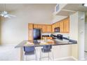 Bright kitchen featuring wooden cabinets, black appliances, and an island with bar seating and a stainless sink at 9585 Pearl Cir # 203, Parker, CO 80134