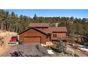 Charming two-story home with an attached two car garage, a manicured lawn, and beautiful landscaping at 24847 Richmond Hill Rd, Conifer, CO 80433