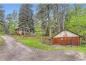 Scenic view of a hillside home with a detached garage, accessible via a gravel driveway amid lush trees and greenery at 30690 Highway 72, Golden, CO 80403