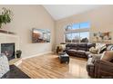 Bright living room with a vaulted ceiling, fireplace, and large windows offering natural light at 5452 Rustic Ave, Firestone, CO 80504
